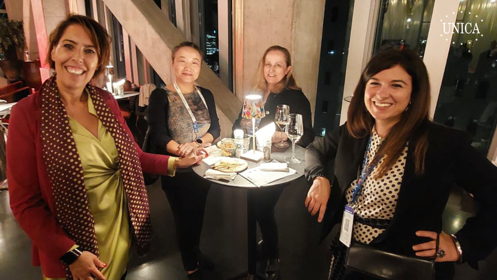 4 women posing for a picture around a high table