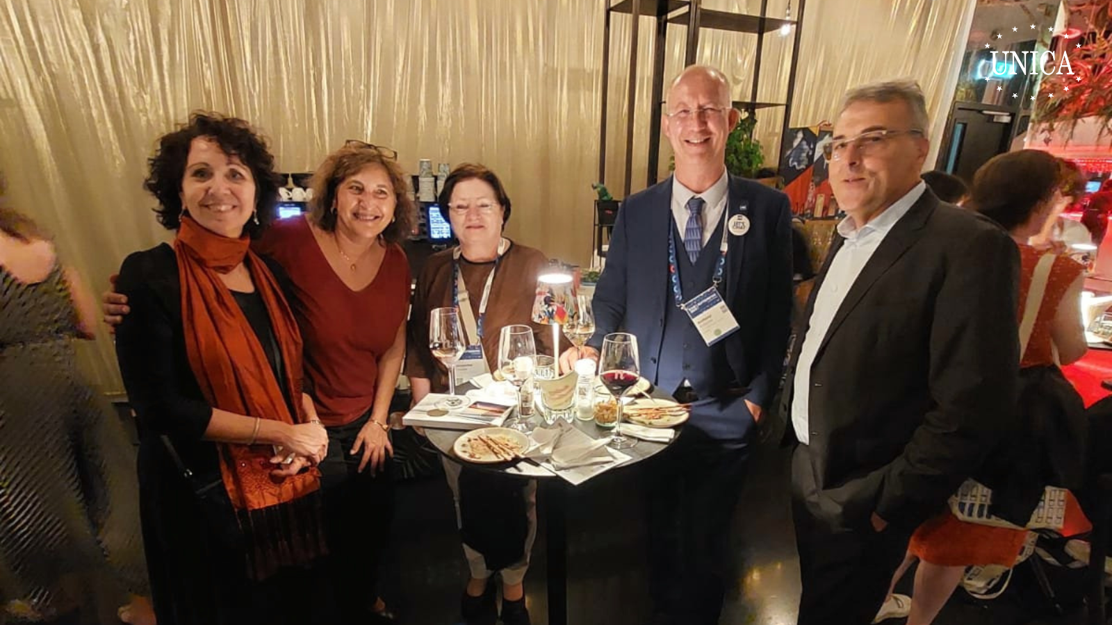 3 women and 2 men posing for a picture around a high table